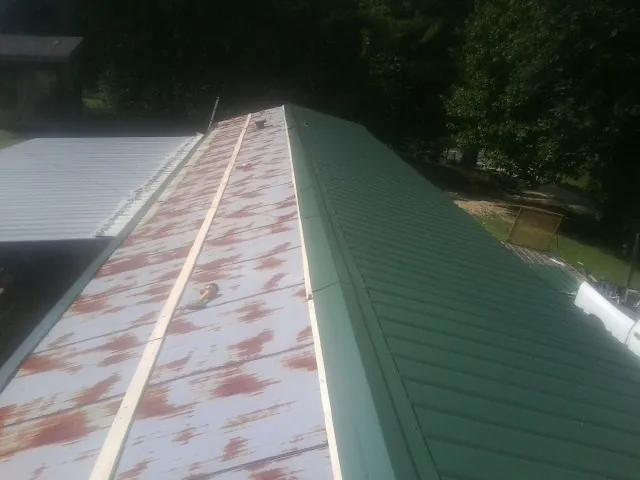 Old rusted panels beside newly installed green metal roofing — Wind Damage Roof Repair by Roofing Brothers in Paragonah