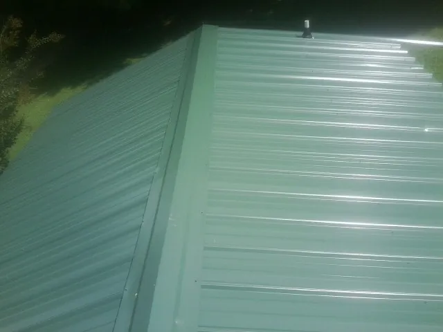 New green metal panels meeting at the ridge of a roof — Flat Roof Repair work by our crew in Paragonah
