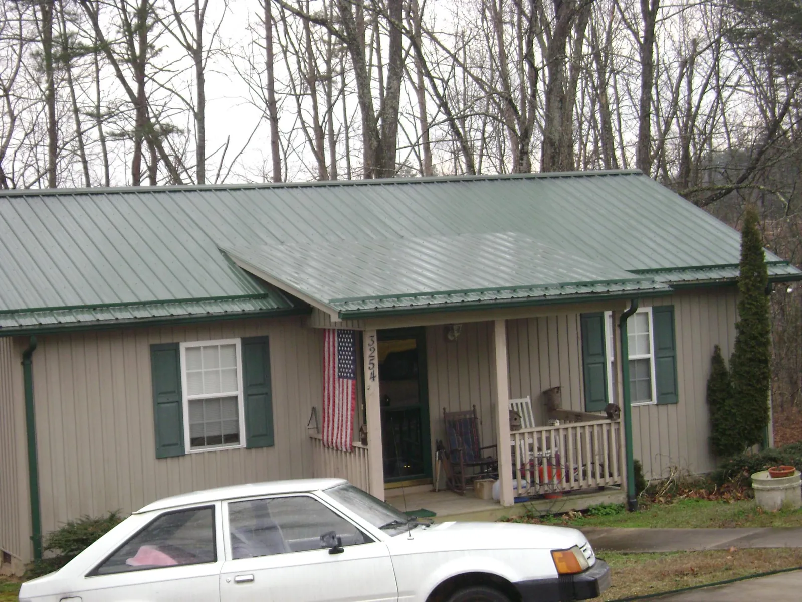 Green metal roof and front porch on a tan sided cottage in Paragonah