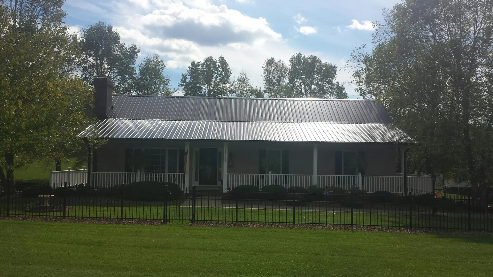 Gray metal roof on a brick ranch with a full width front porch — Gutter Guard Installation work by our crew in Paragonah