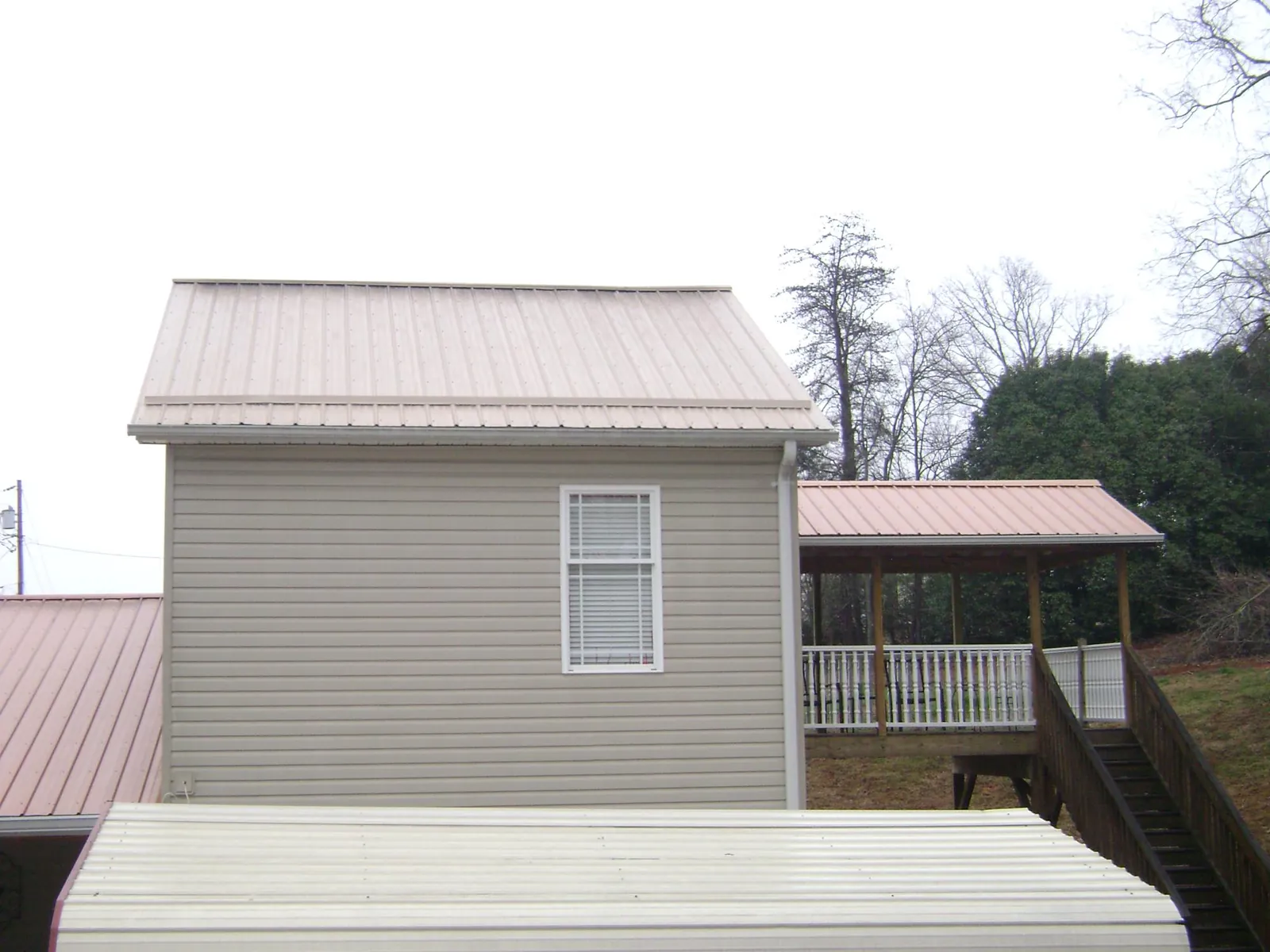 Tan metal roofs on a two story addition and attached porch, from a Roof Replacement job in Paragonah
