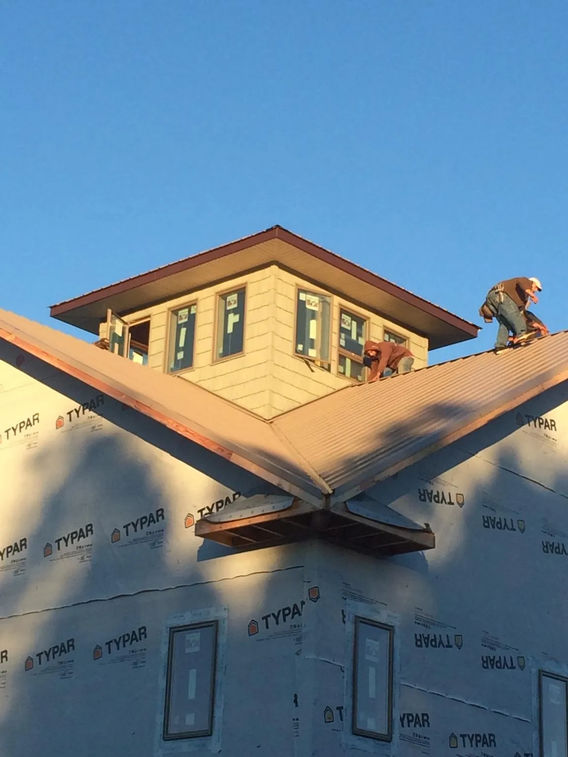 Roofers working around a rooftop cupola on a new metal roof at sunset — Roof Waterproofing in Paragonah by Roofing Brothers